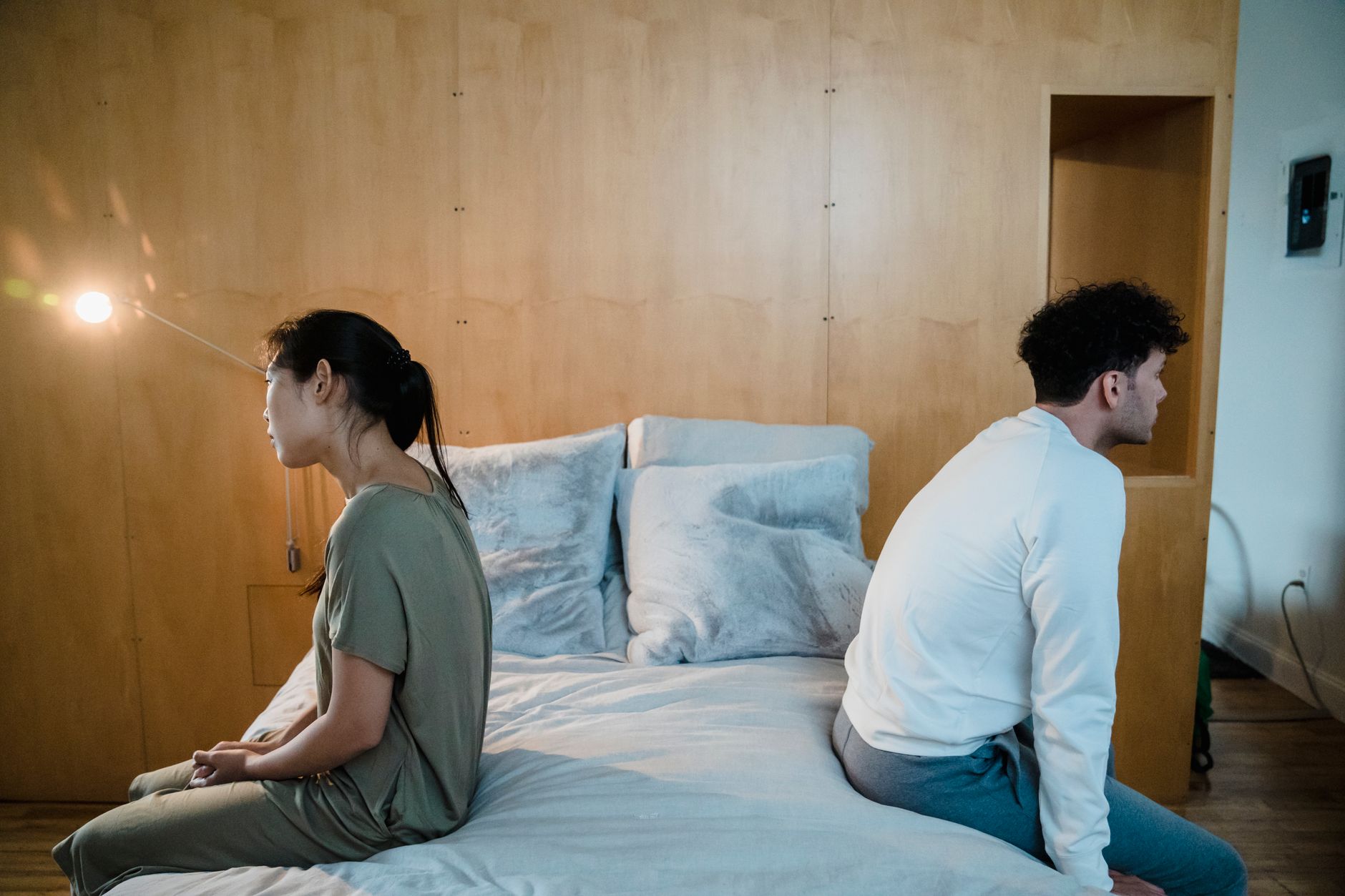 Man en vrouw zitten zwijgend met de rug naar elkaar toe op de rand van het bed